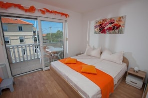 Relax in this serene space with a large bed, sliding glass door to a balcony, and a beautiful painting above.