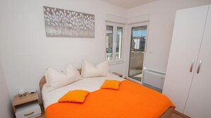 Ein Schlafzimmer mit einem Bett, Kissen, einem Nachttisch, einem Fenster und einem Kleiderschrank.