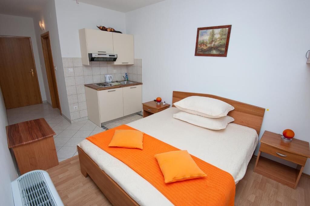 Habitació d'hotel amb llit, taulell, taula petita, un calefactor, cuina americana i un quadre a la paret.