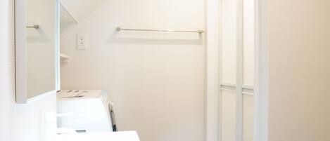 A modern bathroom with a white vanity, a large mirror, and a walk-in shower.