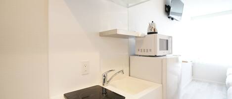 A modern bathroom with a white sink, a built-in microwave, and a ceiling-mounted ventilation system.