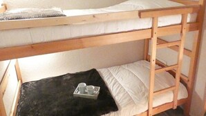 A bunk bed with a black blanket and a tray with two cups. - Cozy studio for 4 in Saint-Lary-Soulan with south-facing balcony (Saint-Lary-Soulan)