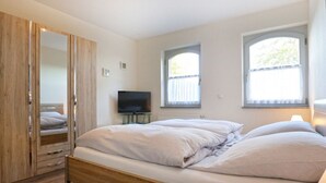 Un dormitorio con una cama de madera, televisión y armario.