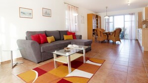 Una sala de estar con sofá, mesa de centro y comedor con sillas y mesa.