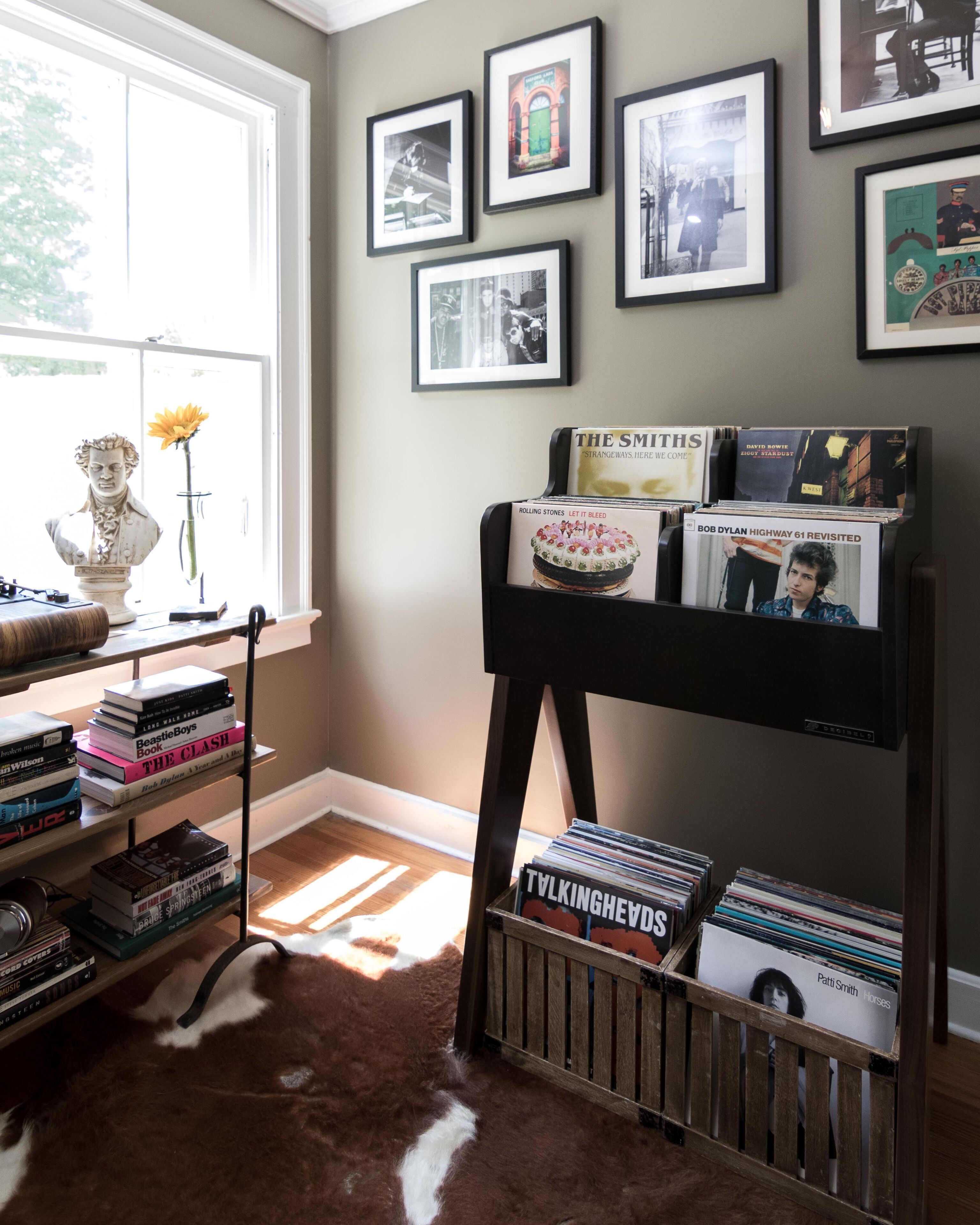 A room with a bookshelf, a bust, and framed pictures on the wall.
