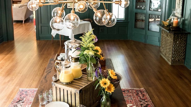 A dining table with pastries, a coffee pot, and a vase of sunflowers. - Granville House (Housatonic)