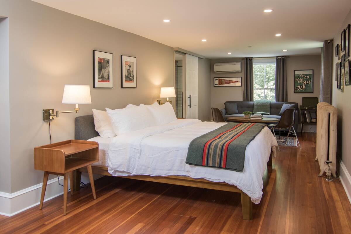 A bedroom with a wooden bed, bedside tables, a desk, and a chair.