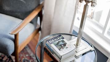 A stack of books on a glass table with a metal lamp.
