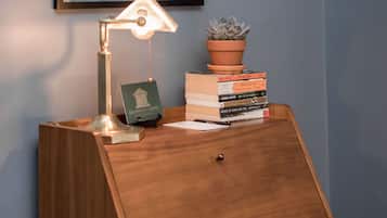 Ein Holztisch mit einer Karte, einer Schreibtischlampe, einer Topfpflanze und einem Stapel Bücher.