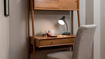 Un espacio de trabajo reducido con un escritorio de madera, una silla, un globo terráqueo, libros y una lámpara.