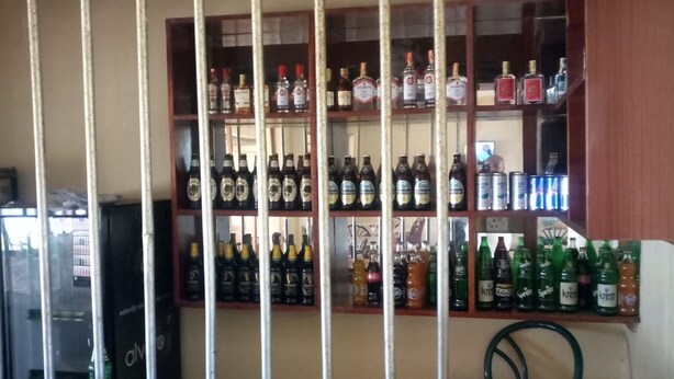 Zona de bar con estantes llenos de botellas de licores y latas.