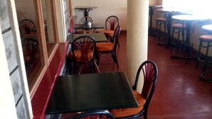 Interior de restaurante con mesas y sillas, piso de baldosas y un ventanal con vistas.