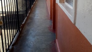Un pasillo con suelo de hormigón, barandilla de metal negro y paredes pintadas de rojo y blanco.