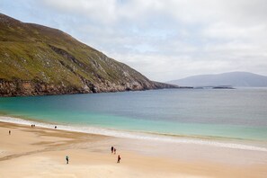 A beach with a rocky hillside and calm waters. - Achill Sound Holiday Village (Achill Island)