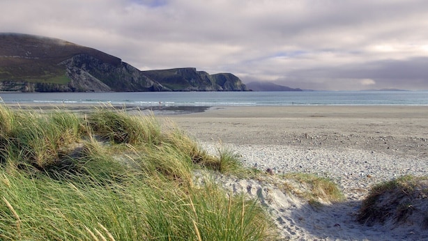 A beach with grassy dunes and rocky cliffs in the background. - Achill Sound Holiday Village (Achill Island)