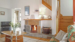A cozy living room with a fireplace, wooden staircase, and a television. - Achill Sound Holiday Village (Achill Island)
