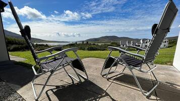 Two folding chairs on a patio with a view of houses and hills in the background.