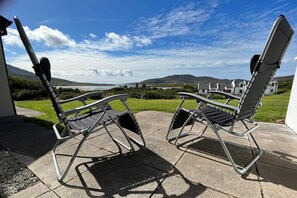Two folding chairs on a patio with a view of houses and hills in the background. - Achill Sound Holiday Village (Achill Island)