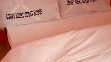 A bed with two pillows that read "COMFY NIGHT GUEST HOUSE".