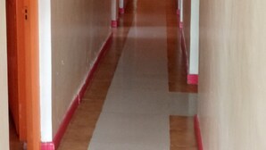 A corridor with a wooden floor and red-tinted walls. - Comfy Night Guest House (Nakuru)