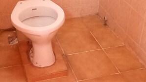 A white toilet in a bathroom with terracotta tiles. - Comfy Night Guest House (Nakuru)