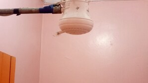 A bathroom with a pink wall, a shower head, and a towel rack. - Comfy Night Guest House (Nakuru)