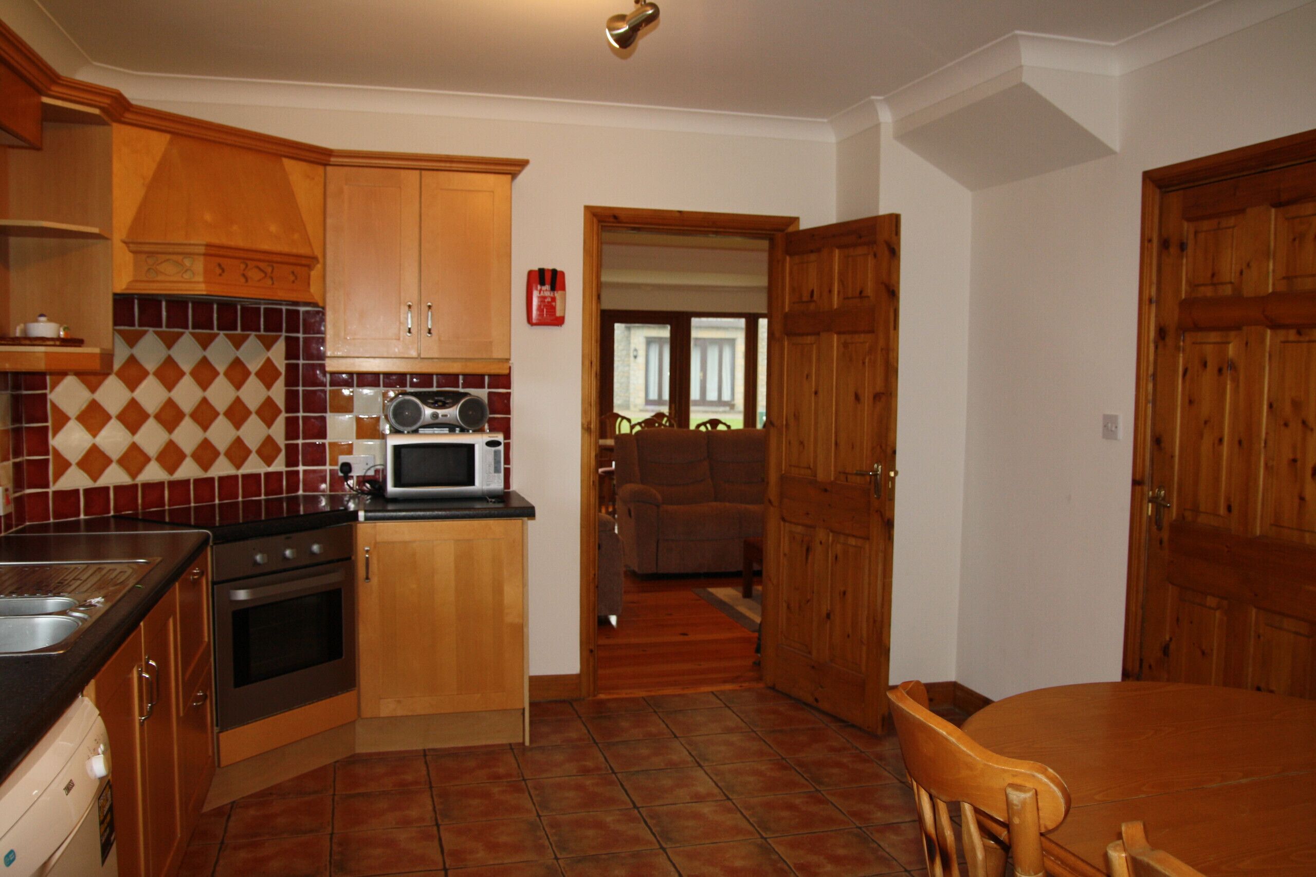 Une cuisine avec des meubles de rangement en bois, un four à micro-ondes et une cuisinière. On y trouve également une table à manger avec des chaises.
