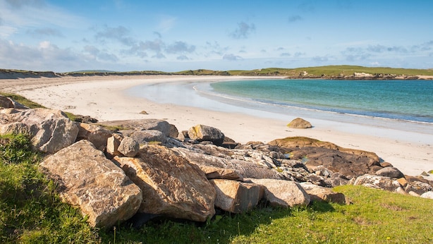 A beach with large rocks in the foreground and a sandy shoreline. - Galway Bay Lodge (Oranmore)