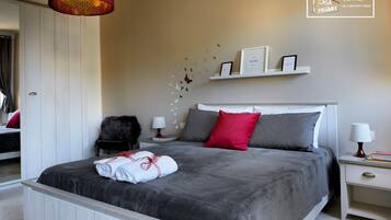 A bedroom with a large bed, a nightstand, a chair, and a hanging lamp.