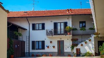 A building with a tiled roof, a rooster mural, and potted plants.