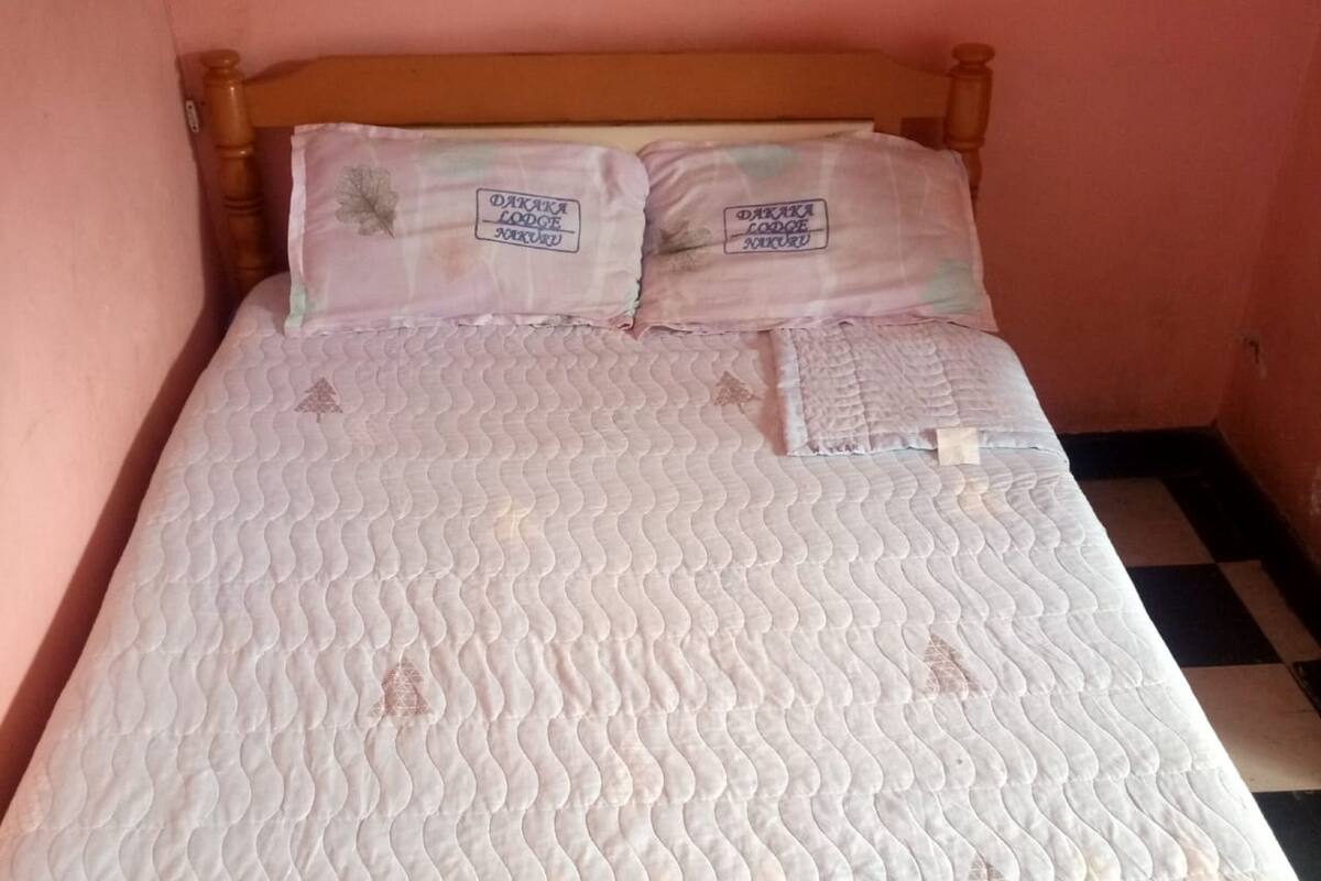 Una cama con un colchón acolchado y dos almohadas con bordados.