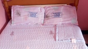 A bed with a quilted white bedspread and two pillows with embroidered text. - Dakaka Lodge (Nakuru)