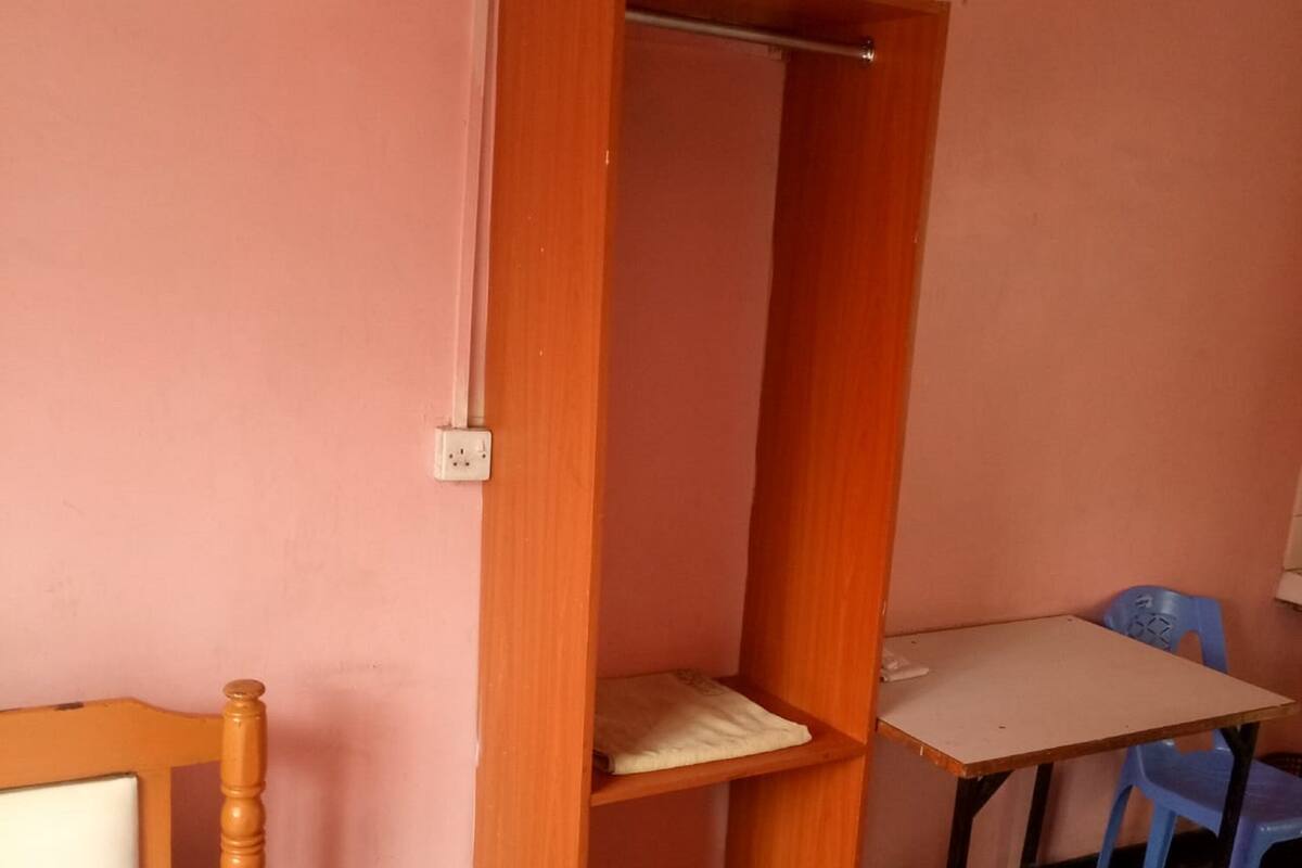 Una habitación pequeña con cama, un armario de madera, una mesa y una silla.