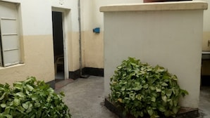 A small, enclosed courtyard with concrete flooring and two potted plants. - Dakaka Lodge (Nakuru)