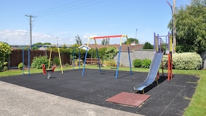 A playground with swings, a slide, and a climbing structure.