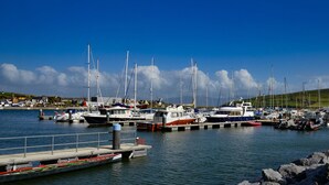 A marina with various boats docked, a pier with a boat, and a clear blue sky. - Fairfield Holiday Home No 13 (Dingle)