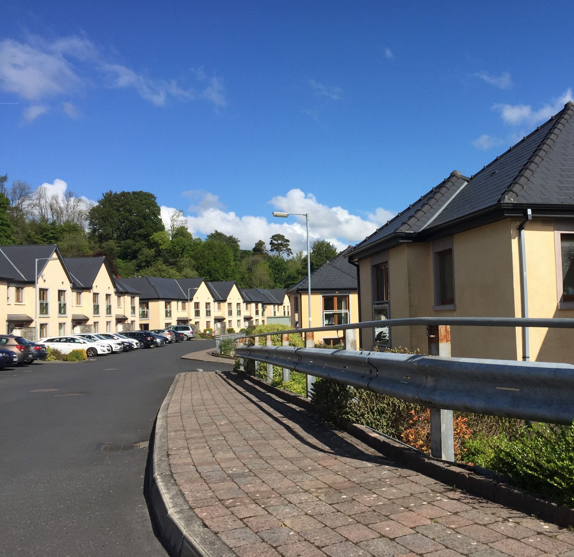 A row of modern, single-story buildings with a uniform architectural style, featuring pitched roofs and a paved parking area in front.