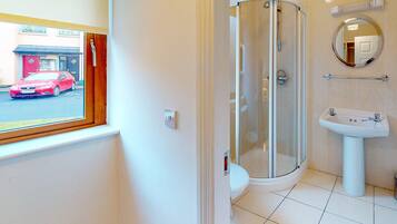 A modern bathroom with a glass-enclosed shower, a white sink, and a mirror.