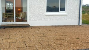 Una casa con fachada blanca, un amplio ventanal corredero y una ventana pequeña.