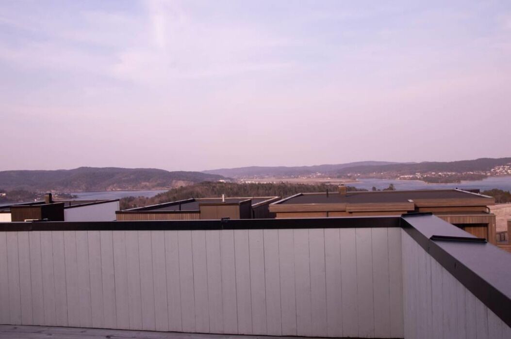 A rooftop with a view of distant hills and a body of water.