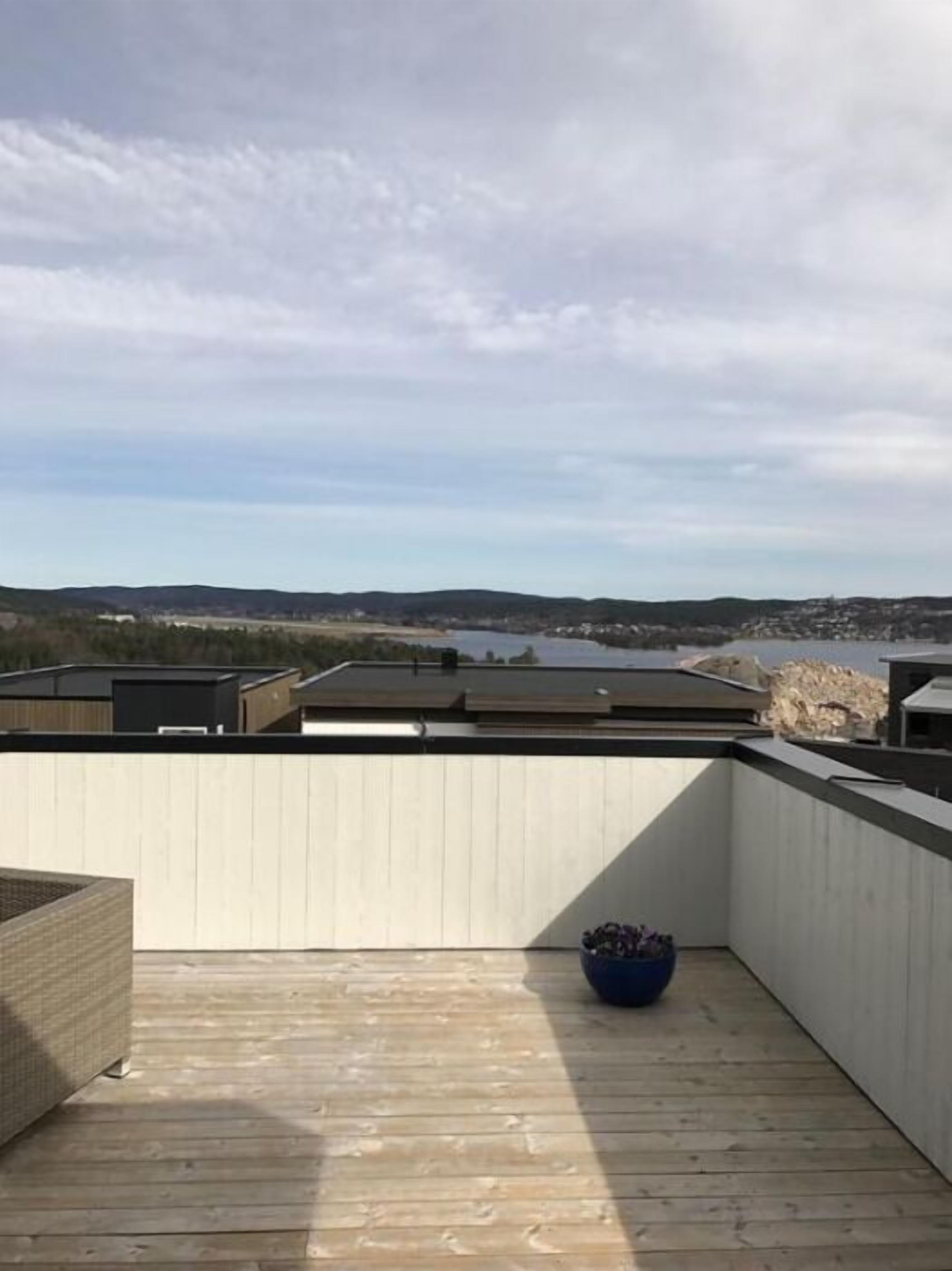 A wooden deck with a view of a lake and distant hills.