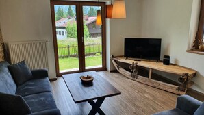Ett vardagsrum med ett stort fönster, en tv på ett träställ och en soffa.
