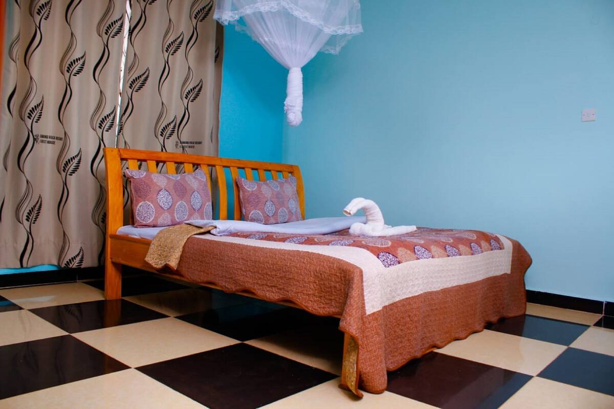 A bed with a patterned bedspread, pillows, and a white swan decoration.