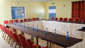 A conference room with a long table, red chairs, and water bottles. - Diamond Rock Resort & Guest House (Kakamega)