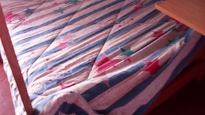 Una cama individual con una colcha a rayas y una almohada blanca.