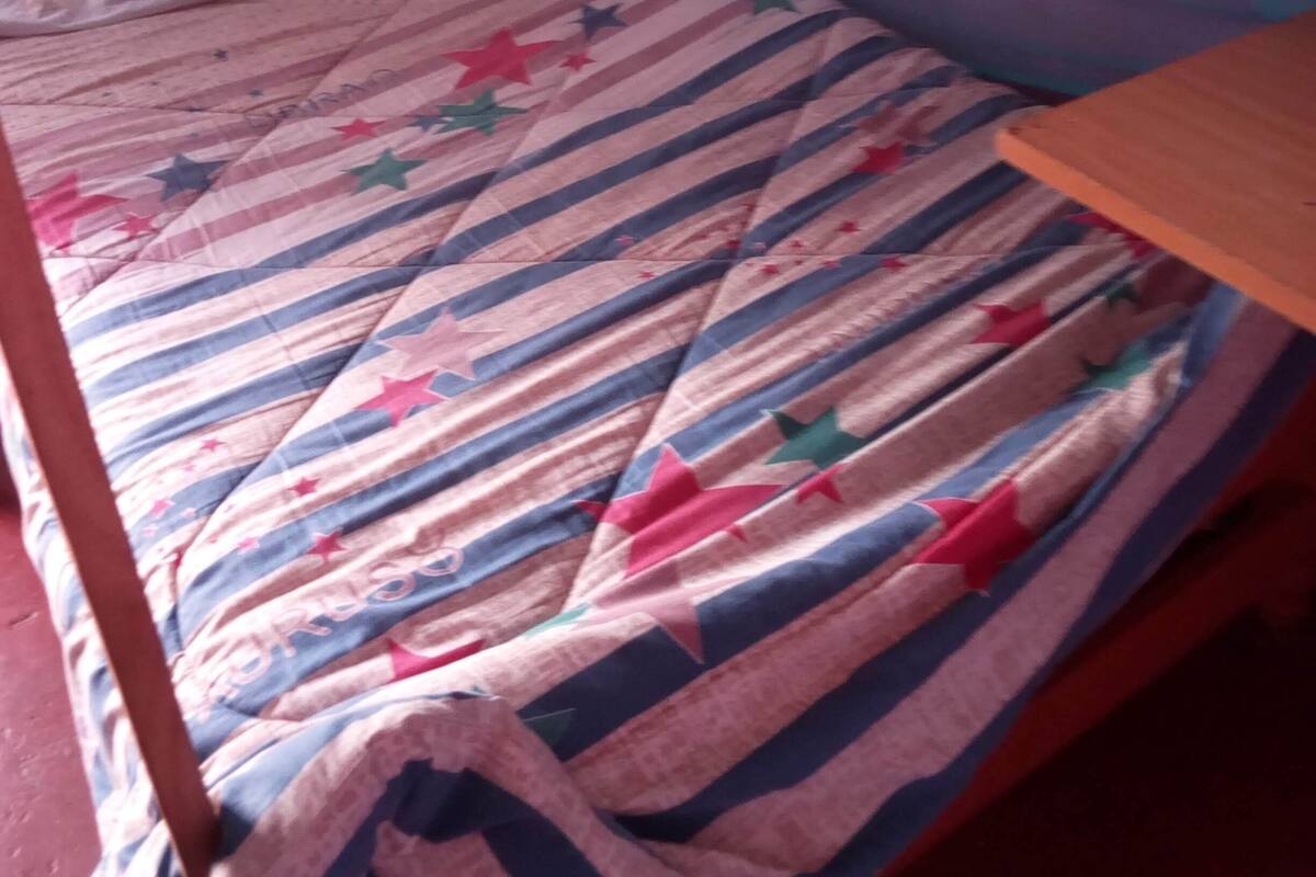 A single bed with a striped bedspread and a white pillow.