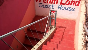 Una escalera conduce a la 'Dream Land Guest House', con una pared roja y barandilla de metal.