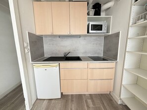 Een koelkast, een microgolfoven, kookgerei, borden en bestek