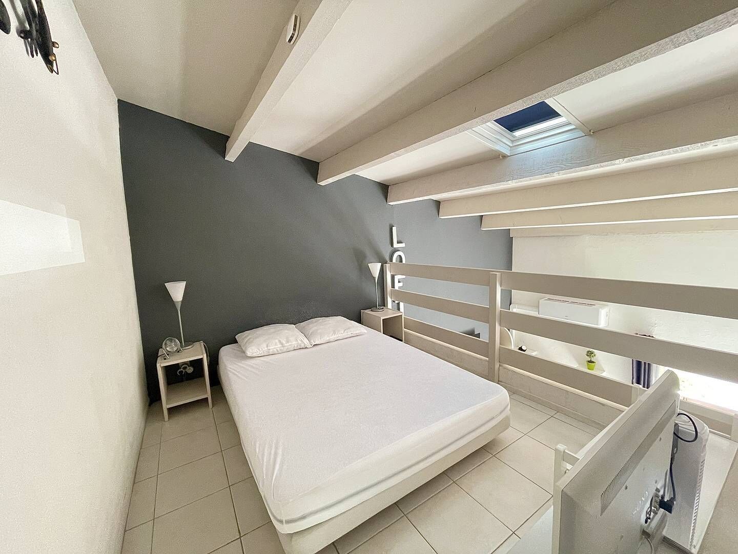 Una camera da letto compatta con un letto, un comodino, una scrivania e una piccola finestra.