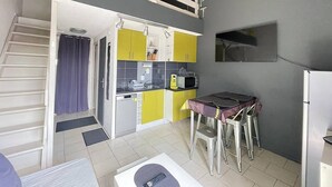 Uma cozinha compacta com área de refeições, micro-ondas embutido e geladeira.